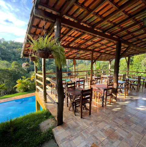 área para refeições e trabalhar com bela vista para floresta e piscina da pousada recanto do chalé