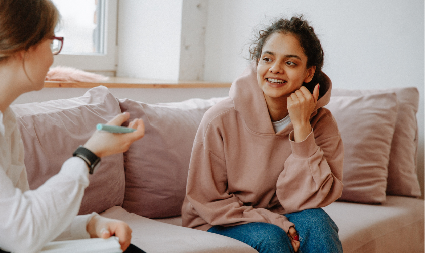 hispanic teen girl sitting on a couch speaking to an adult