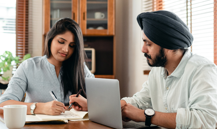 punjabi father and daughter sitting at table doing paperwork