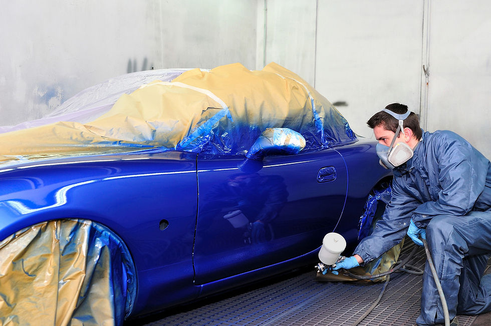A technician spray-painting on a car.