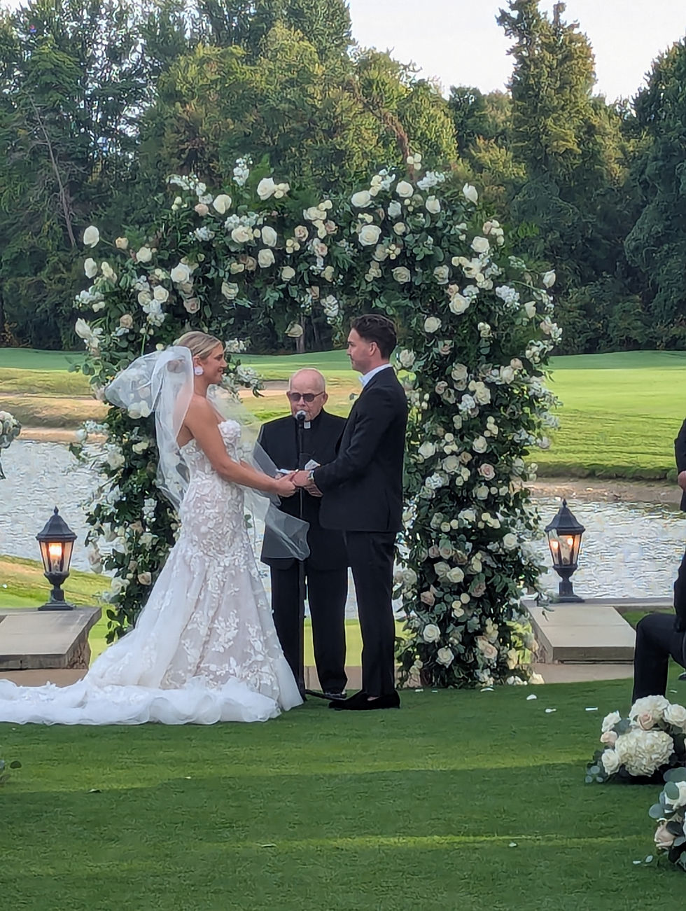 Wedding at Cherry Creek Golf Club outside next to the lake. White flower arch behind the couple. Music by Rondo String Quartet.
