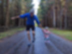 A hiker and his daughter running through a forest.