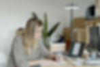 Woman writing at a desk with laptop and boxes