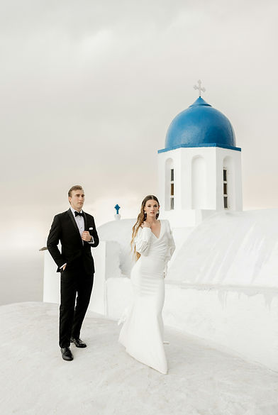 Wedding couple on a traditional white terrace in Santorini, Greece, overlooking the sea during their destination wedding.