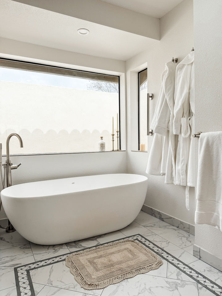 Modern bathroom with a bathtub, towels, and window overlooking the outside.