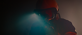 Firefighter wearing helmet, goggles, shining bright light through dark smoke.