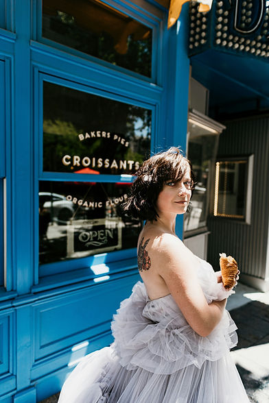 Chic bride posing in front of a traditional Parisian boulangerie during a sophisticated city elopement in a European capital.
