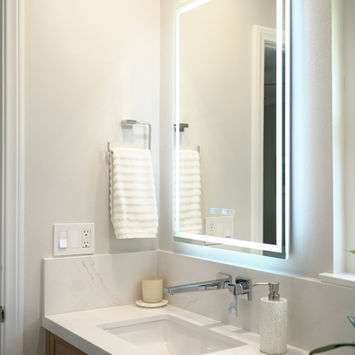 Custom bathroom vanity with illuminated mirror and chrome wall-mounted faucet