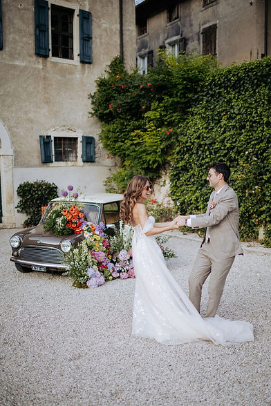 Newlyweds celebrating in front a vintage Italian car, capturing the authentic Dolce Vita essence of a destination wedding in Italy.