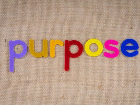 Colourful letters on brown linen material that spells out the word "purpose."