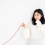 赤い糸を指に結ぶ女性