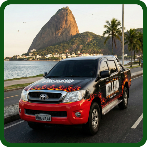 Caminhonete preta e vermelha com envelopamento personalizado estacionada na orla com o Pão de Açúcar ao fundo.