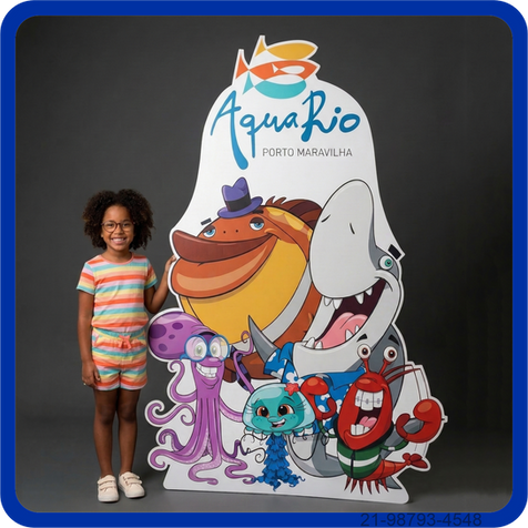Menina sorrindo ao lado de painel instagramável infantil com personagens marinhos do AquaRio.