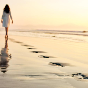 Empreintes de pas sur une plage, symbolisant le chemin parcouru et le récit de soi.