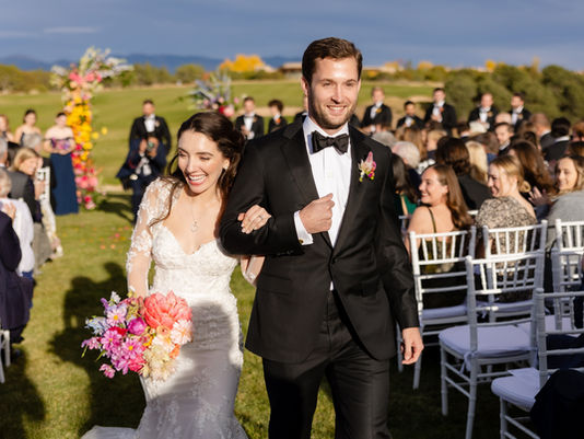 Bride and groom walk down aisle after getting married on golf course.