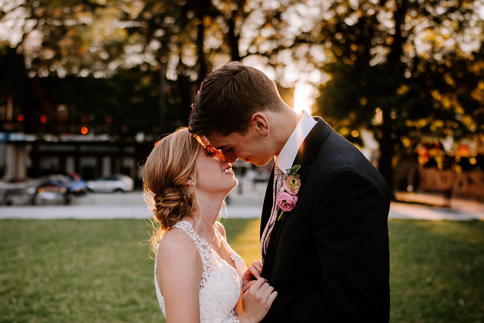 A bride and groom about to kiss at sunset.