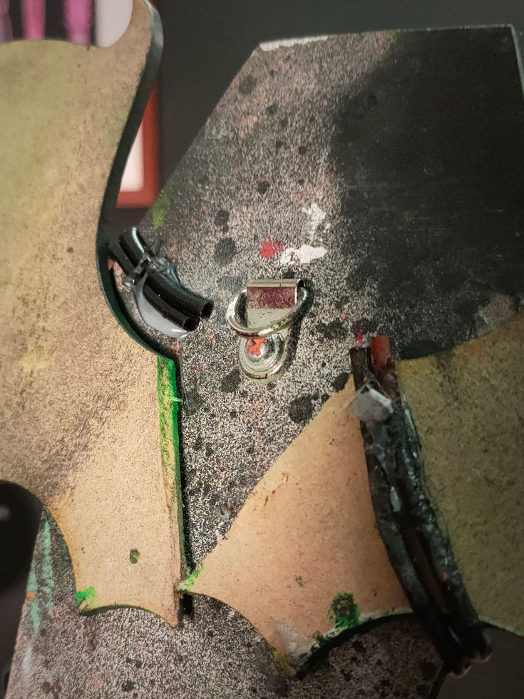 close up view of the hanging fixture on the back of black coffin sculpture with bat wings