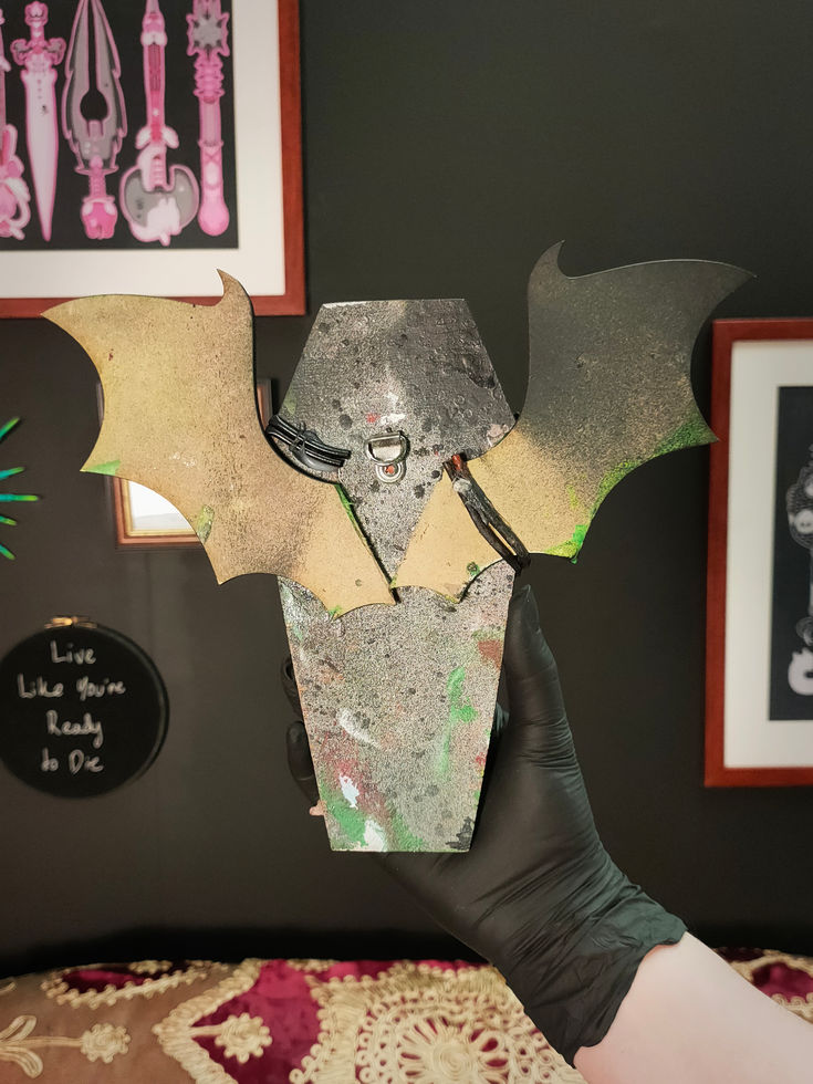 back view of black coffin sculpture with bat wings