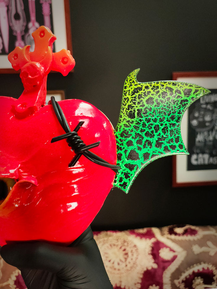front right view of vibrant red sacred heart sculpture with green crackle bat wings