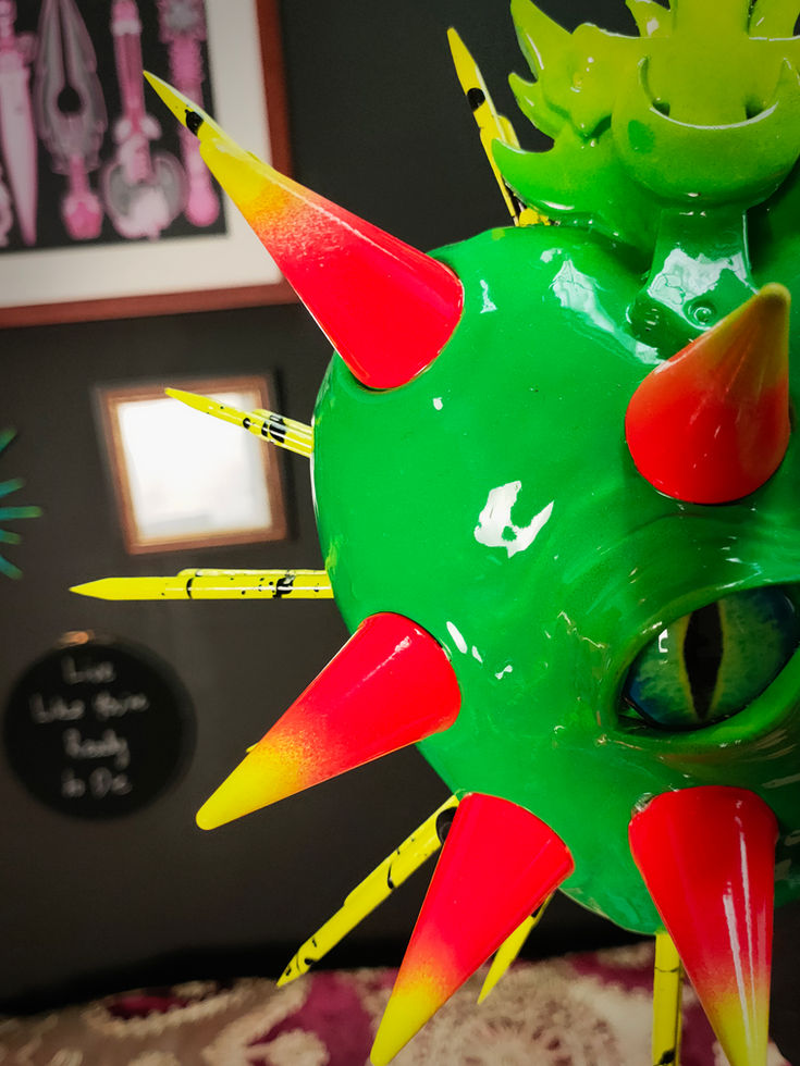 front left view of vibrant green sacred heart sculpture with orange and yellow conical spikes.