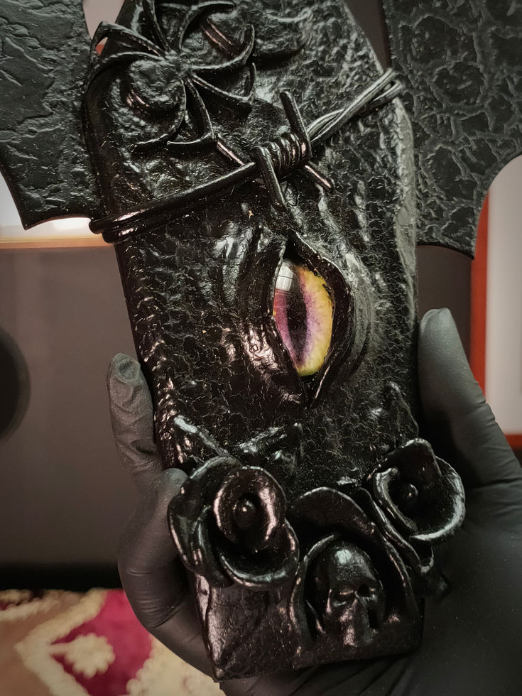 close up view of black coffin sculpture with bat wings central eye detail
