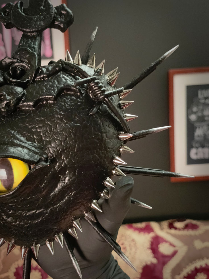 front right view of black spiked sacred heart with yellow eye