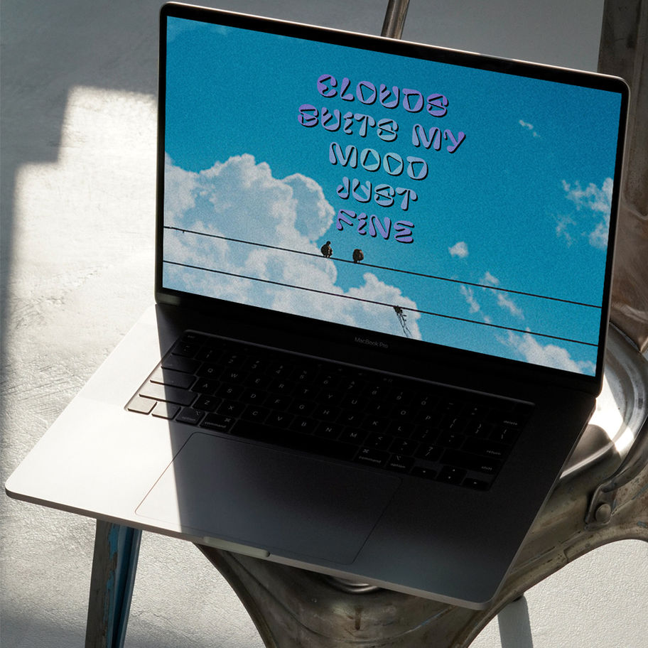 Laptop screen displays "Clouds Boost My Mood Just Fine" message and sky backdrop.