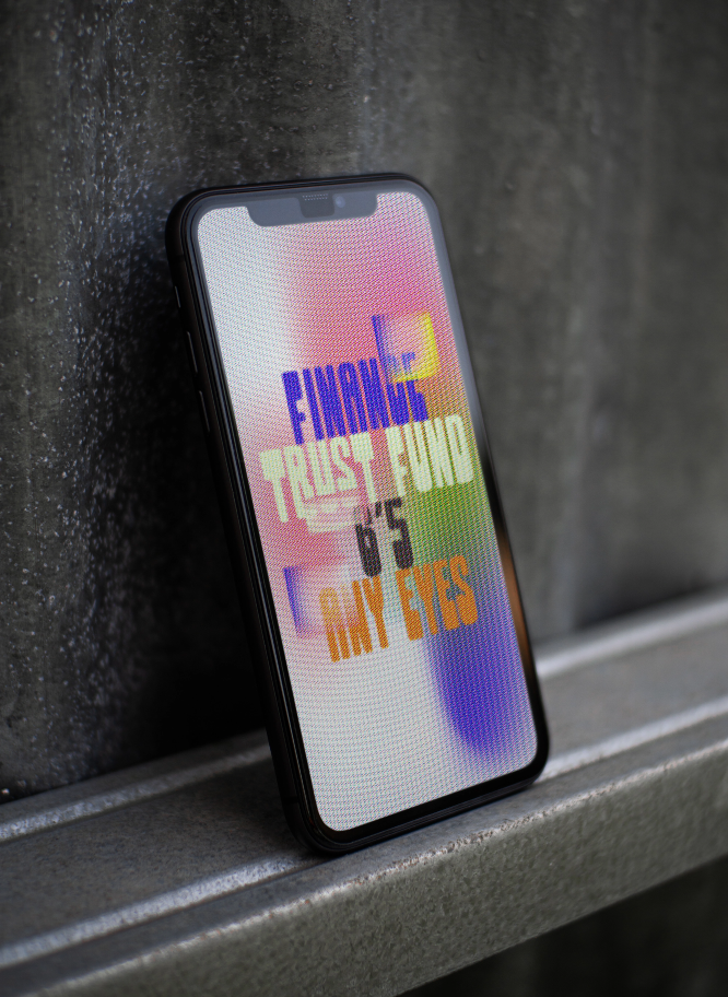 Smartphone screen displays text: FINAN TRUST FUND & ITS WAY EYES, leaning on surface.