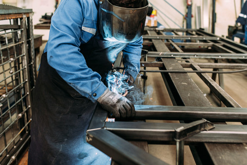Arbeiter mit Schweißer Maske schweißt am Arbeitsplatz
