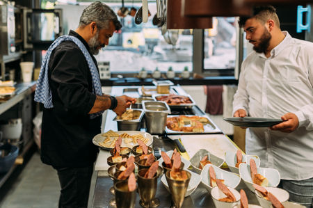 Zwei Köche mittleren Alters berieten in einer Restaurant Küche ein Buffet vor. 