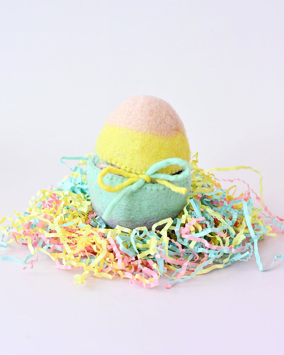Thumbnail: Handmade felt Easter egg by Tara Treasures tied with pastel ribbon and resting in colorful paper grass