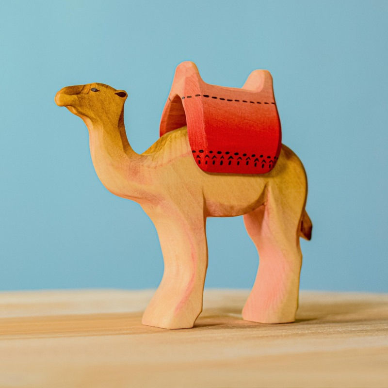 Handcrafted wooden camel with saddle on blue background by Bumbu Toys