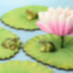 Thumbnail: Wooden frogs sitting on green lily pads around a pink lotus flower, handmade by Bumbu Toys