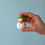 Thumbnail: Hand holding Bumbu Toys Wooden Snowman Birthday Ring Ornament to show size and hand-painted winter details.