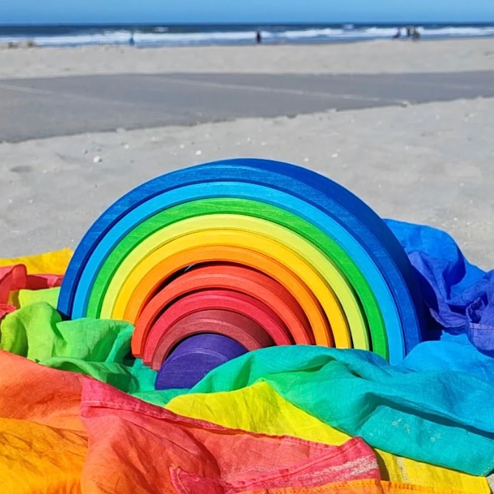 Thumbnail: The Laura's Play cotton Rainbow play cloth is laid under a Grimm's Rainbow Stacker