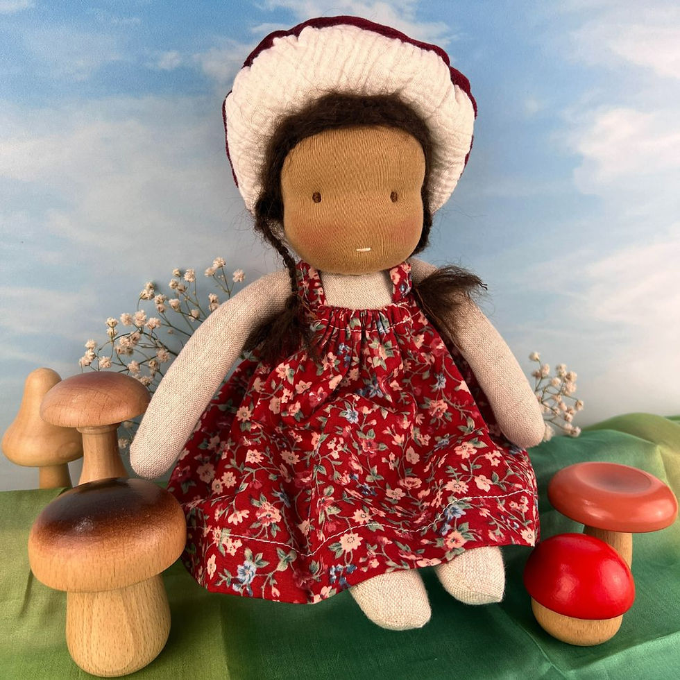 Handmade Waldorf Doll in red floral dress sitting on a green playsilk next to wooden mushrooms