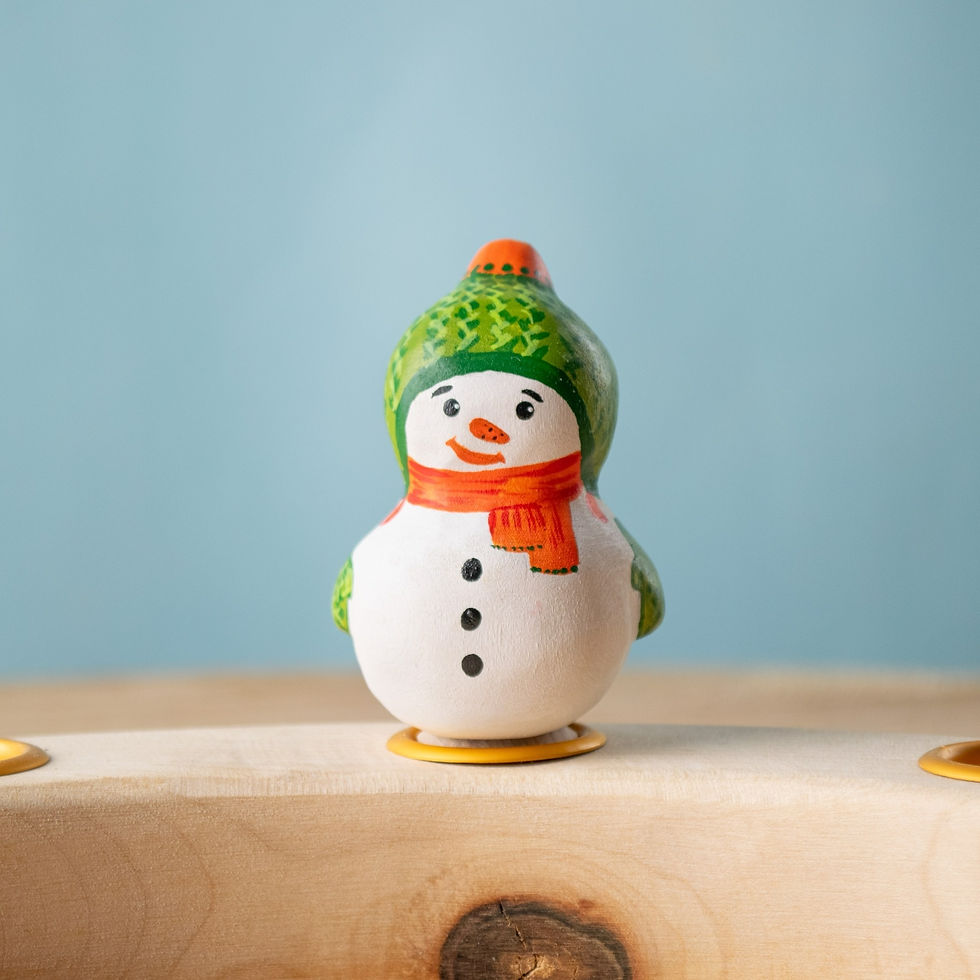 Bumbu Toys Wooden Snowman Birthday Ring Ornament on wooden celebration ring, wearing a green hat and orange scarf.