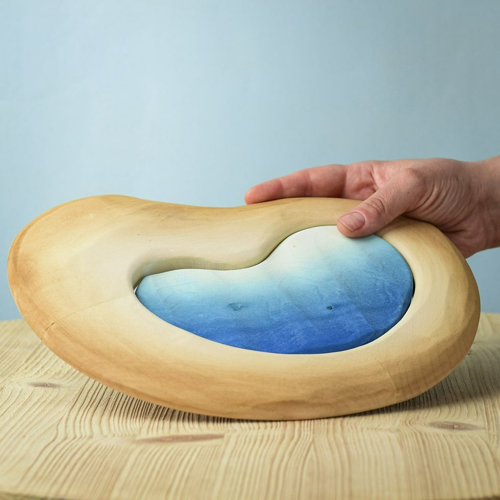 Thumbnail: Bumbu Toys Handcrafted Wooden Savanna Lake toy being held in hand to show its size and craftsmanship on a wooden surface