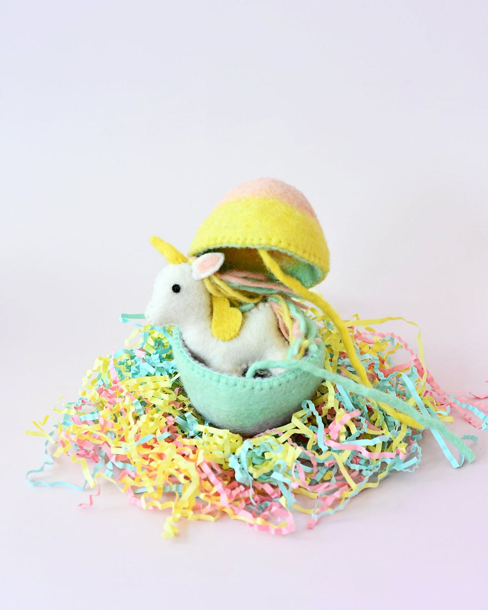 Thumbnail: Felt surprise egg by Tara Treasures with rainbow unicorn toy inside surrounded by pastel Easter paper grass