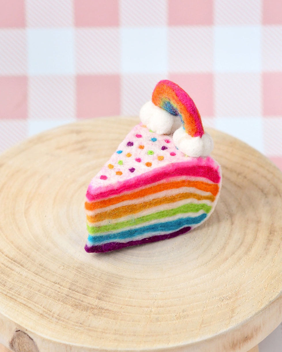 Tara Treasures Felt Rainbow Cake Slice on a rustic wooden stand