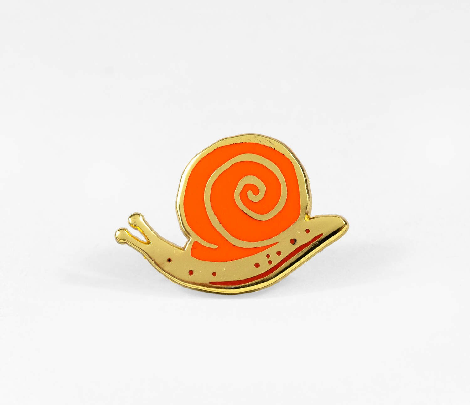 Snail enamel pin by Phoebe Wahl with orange spiral shell and gold tone metal