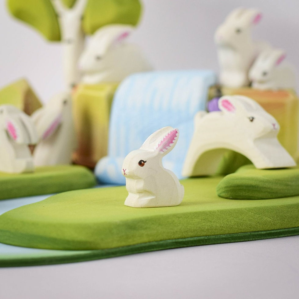 Bumbu Toys Wooden Sitting Easter Baby Rabbit on a green platform surrounded with trees and a waterfall background