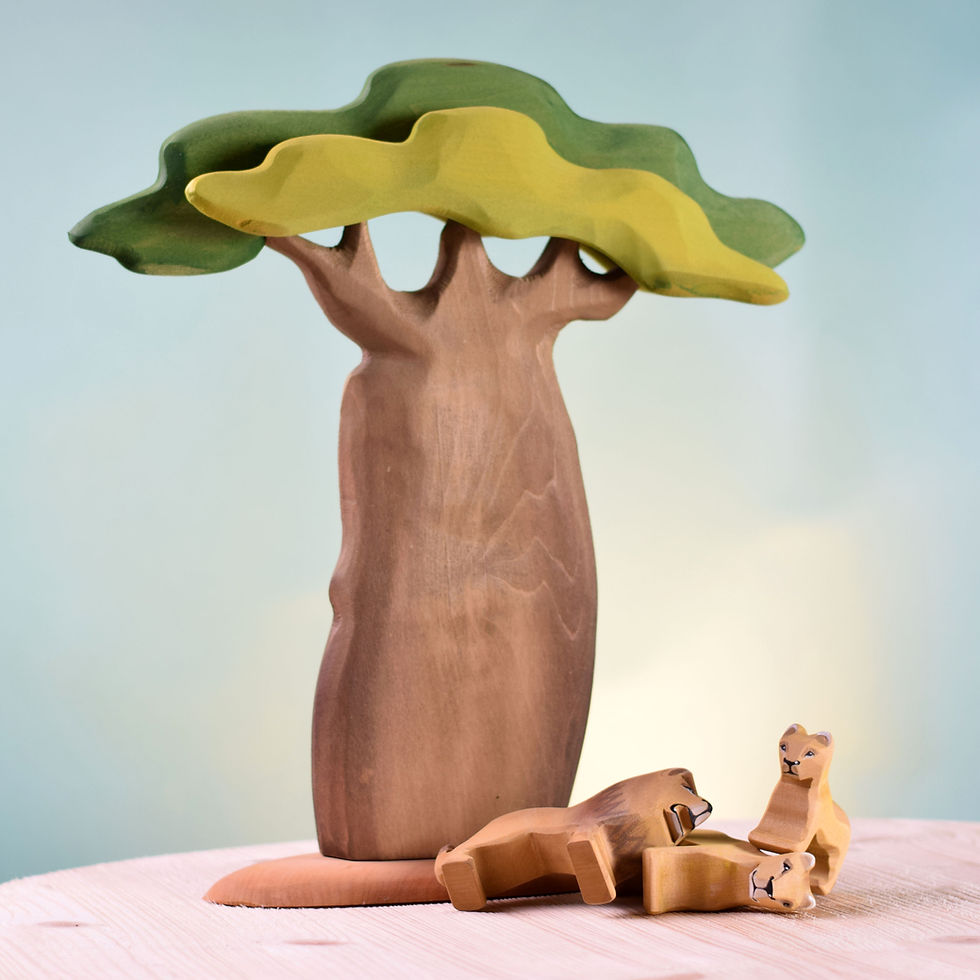 Thumbnail: Bumbu Toys Wooden Lion Figurines in front of a wooden baobab tree on a wooden surface