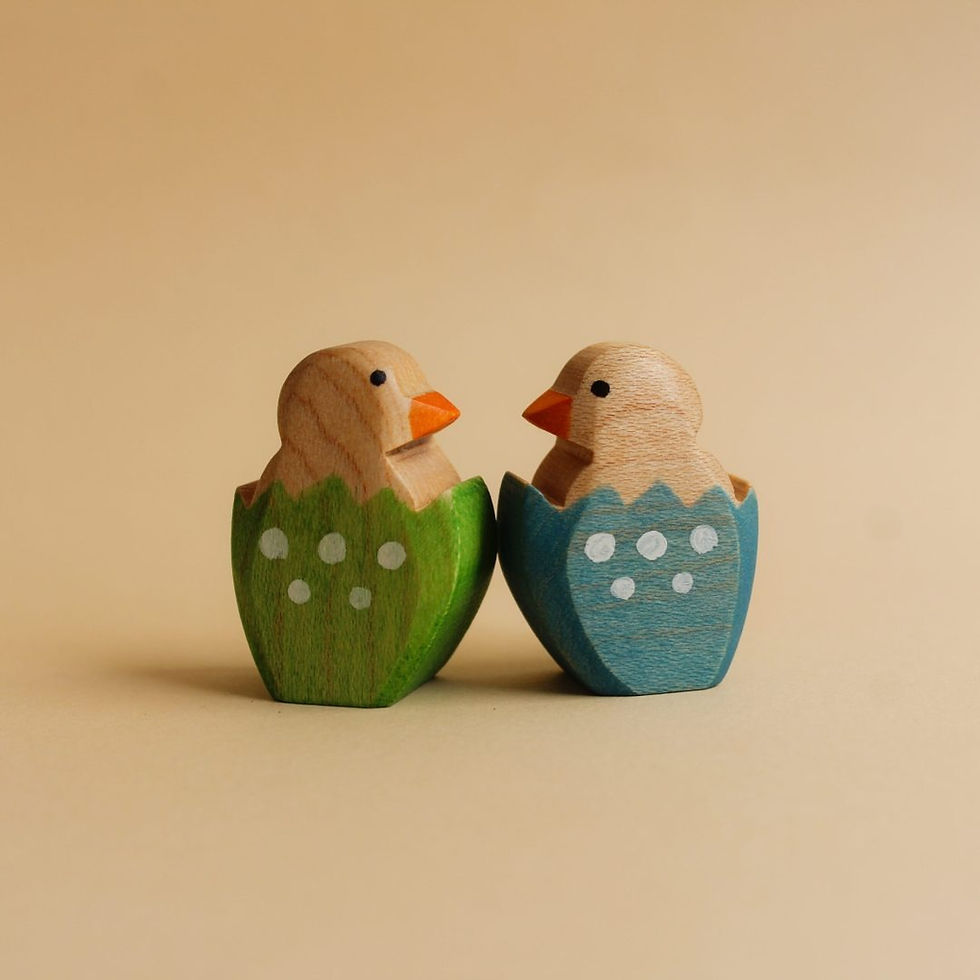 Thumbnail: ide view of a mini Juharka Wooden Chicks in a cracked blue and green eggshell with light blue polka dots.Maple wood bird toy.