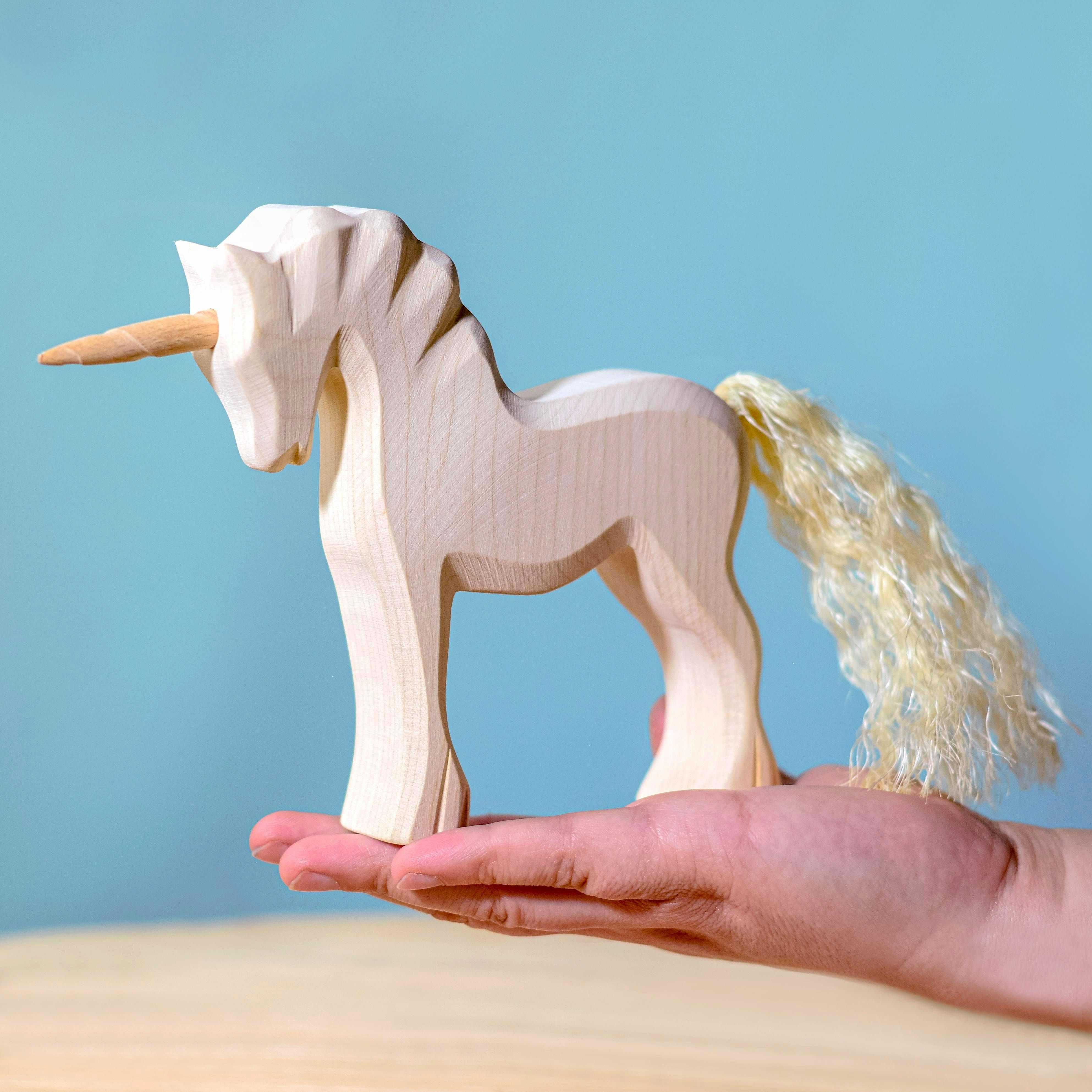 A hand holding the Bumbu Toys Handmade Wooden Unicorn-Natural