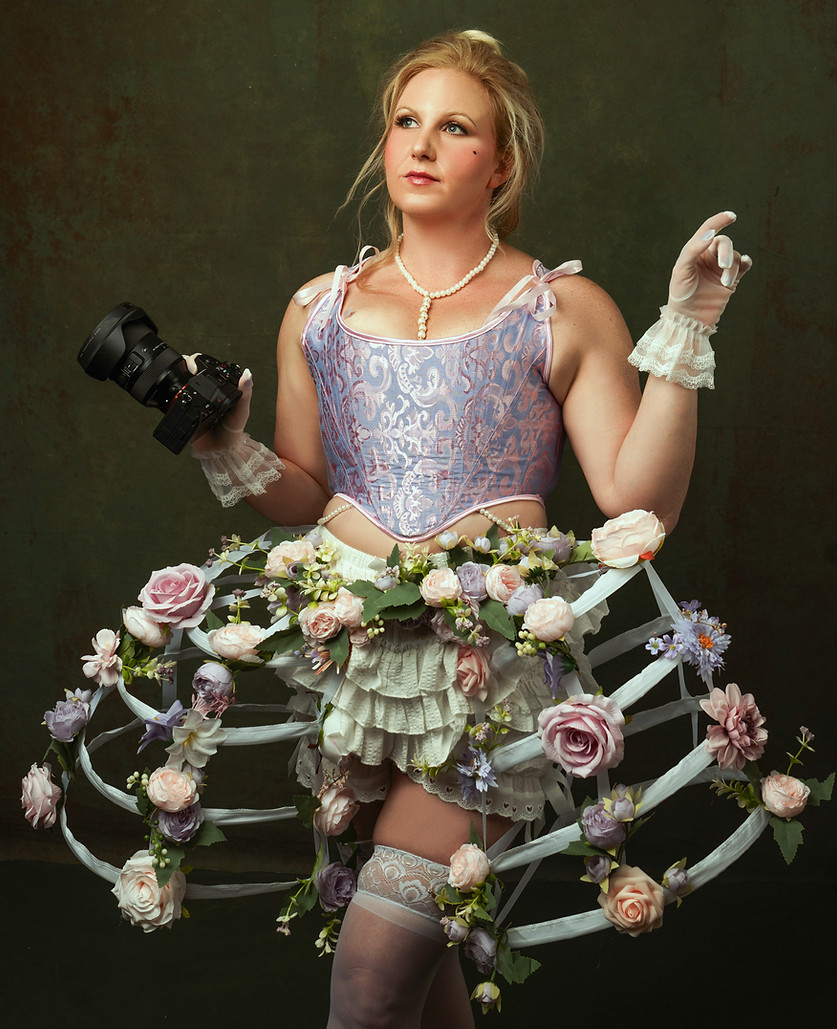A person dressed in a whimsical, floral-themed costume featuring a lavender corset, hoop skirt adorned with artificial flower
