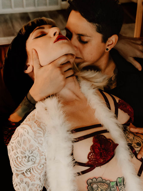 Intimate couple portrait with tattooed partners in white lace and lingerie, captured in warm golden light
