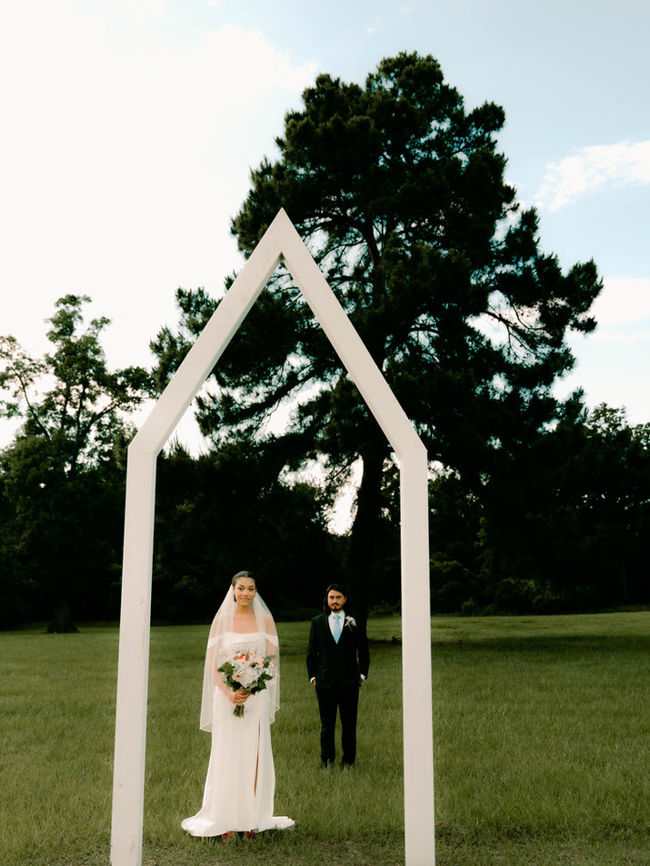 Bride and groom standing under a arch on their wedding day in Austin, Texas, captured by Brittany Berrish Photography