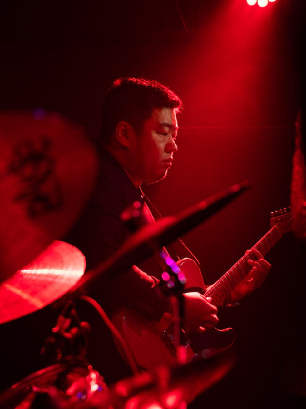Sunset Crave guitarist performing live under red stage lighting