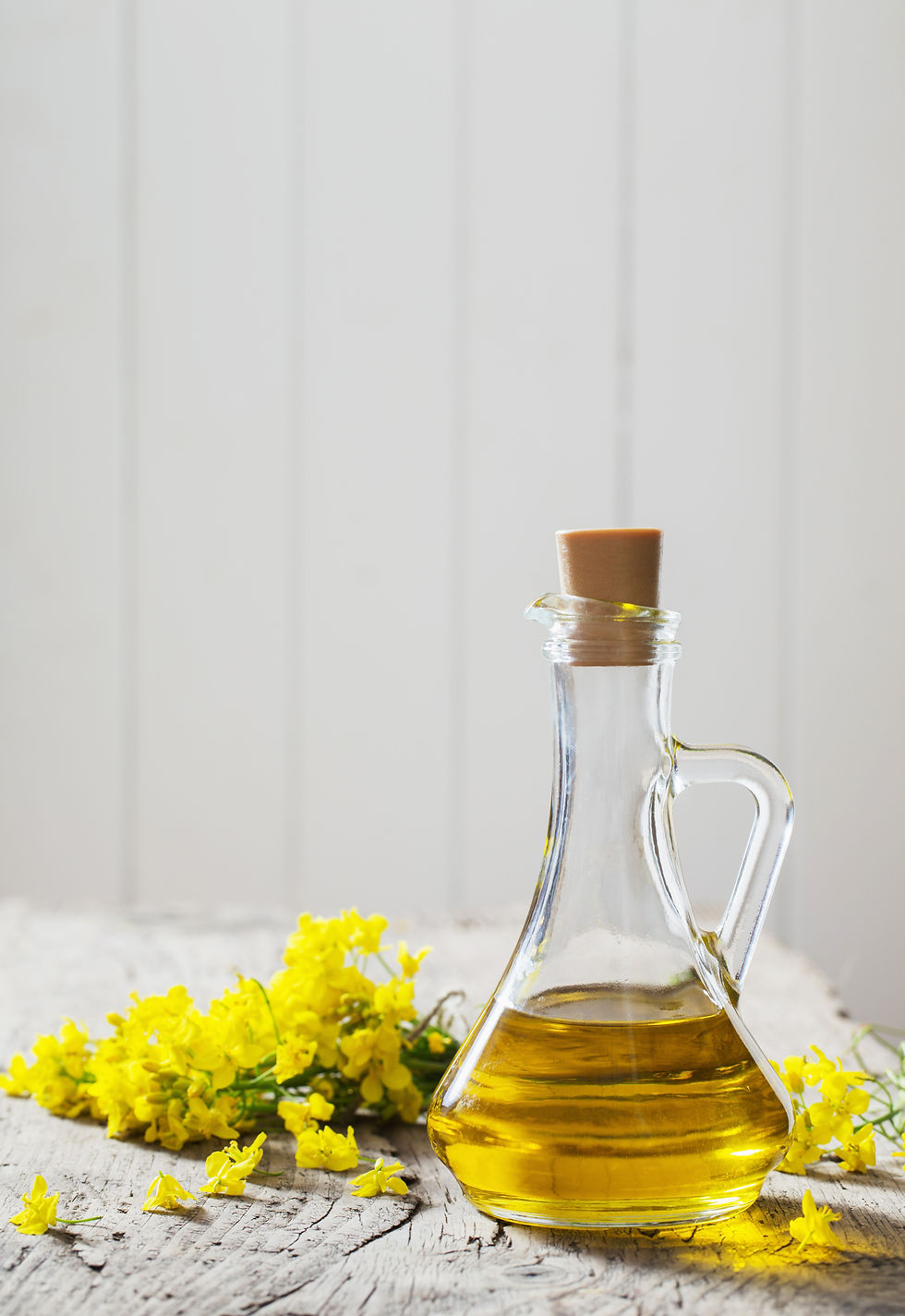 rapeseed oil (canola) and rape flowers on wooden table.jpg